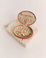 Open jewelry case with rings displayed inside on a textured surface.
