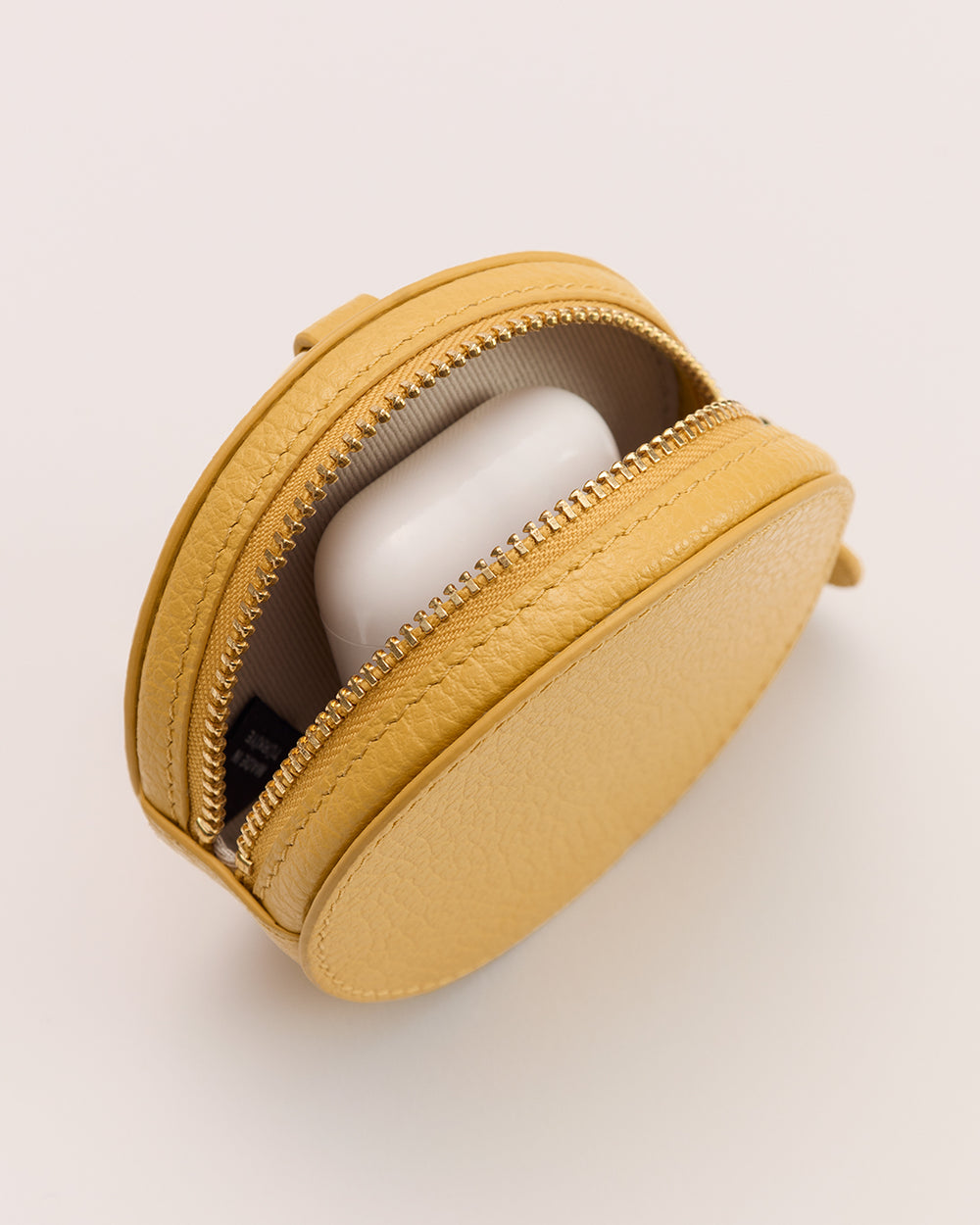 Round zip pouch with an open zipper revealing earbuds case inside.