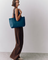 Person carrying a large shoulder bag wearing a long dress and flats.