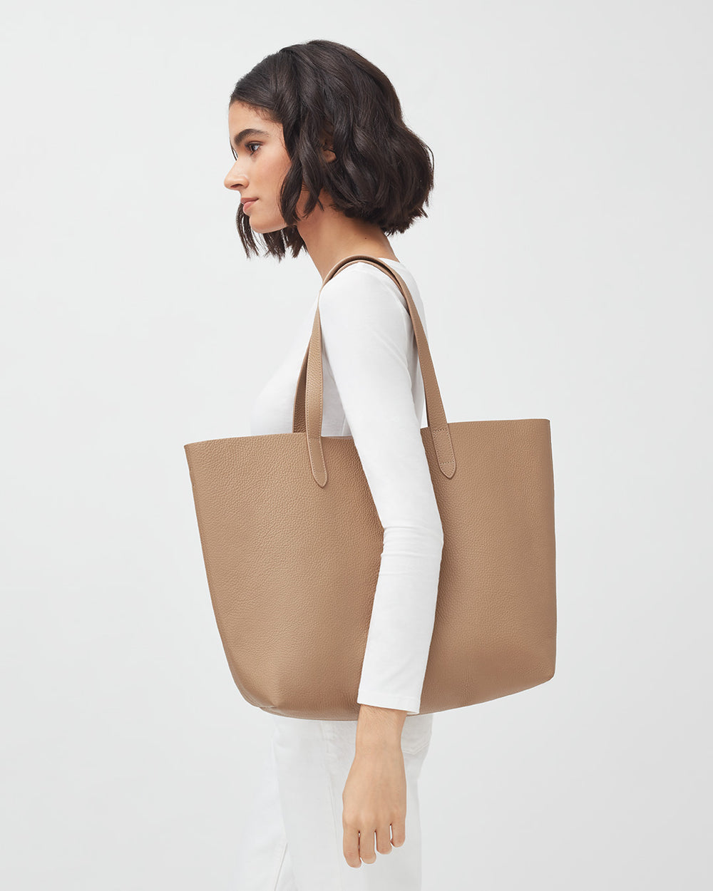 Woman in profile carrying a large tote bag