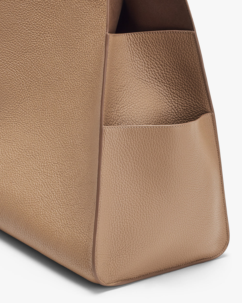 Close-up of a textured handbag with a visible side pocket.