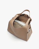 Open handbag with visible contents including a smaller pouch and a book.