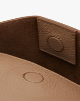Close-up of a textured bag with flap and snap closure.