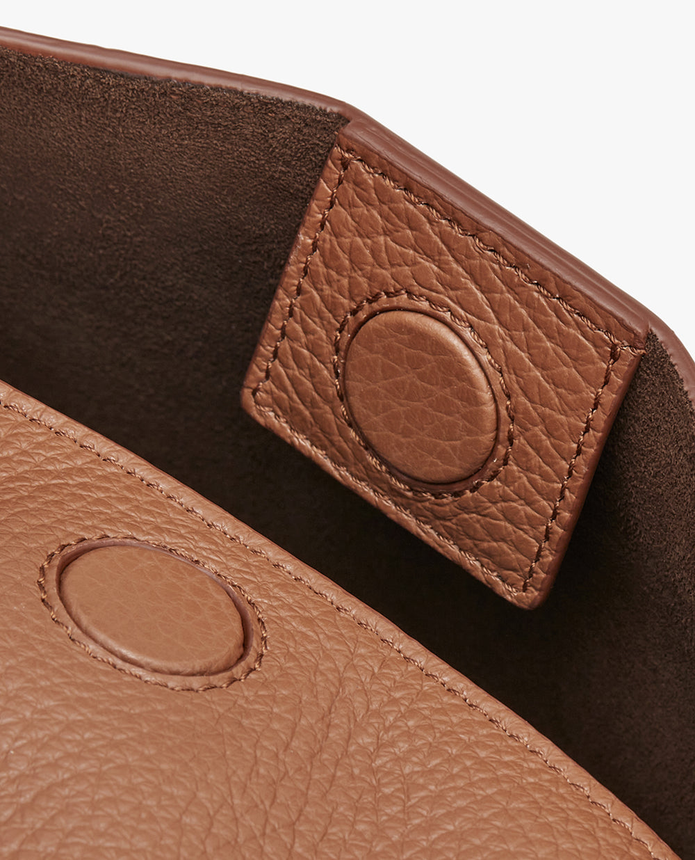 Close-up view of a textured handbag with a flap and button closure.