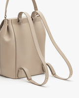 Leather backpack with handles and a shoulder strap standing upright.