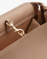 Close-up of a handbag with a metal clasp and interior compartments.