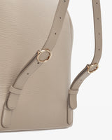 Close-up of a handbag with straps and metallic rings.