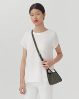 Woman standing with a messenger bag across her shoulder.