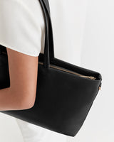 Person holding a handbag with a zipper closure.