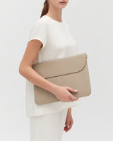 Person holding a large leather laptop sleeve