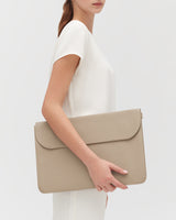 Person holding a large leather laptop sleeve