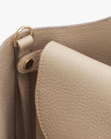 Close-up of a handbag with a focus on its handle attachment and stitching.
