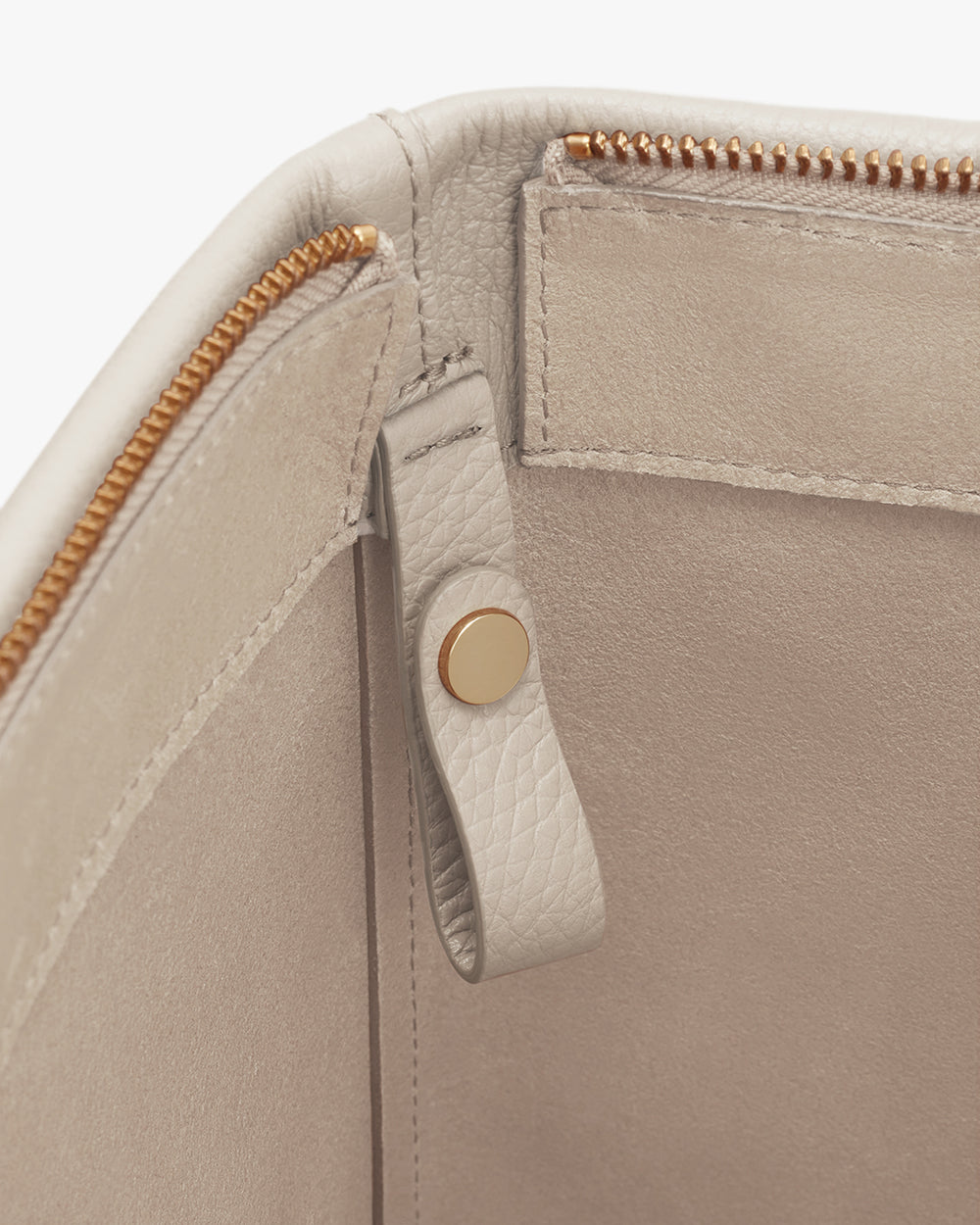 Close-up of a bag with a zipper and a snap button on a flap.