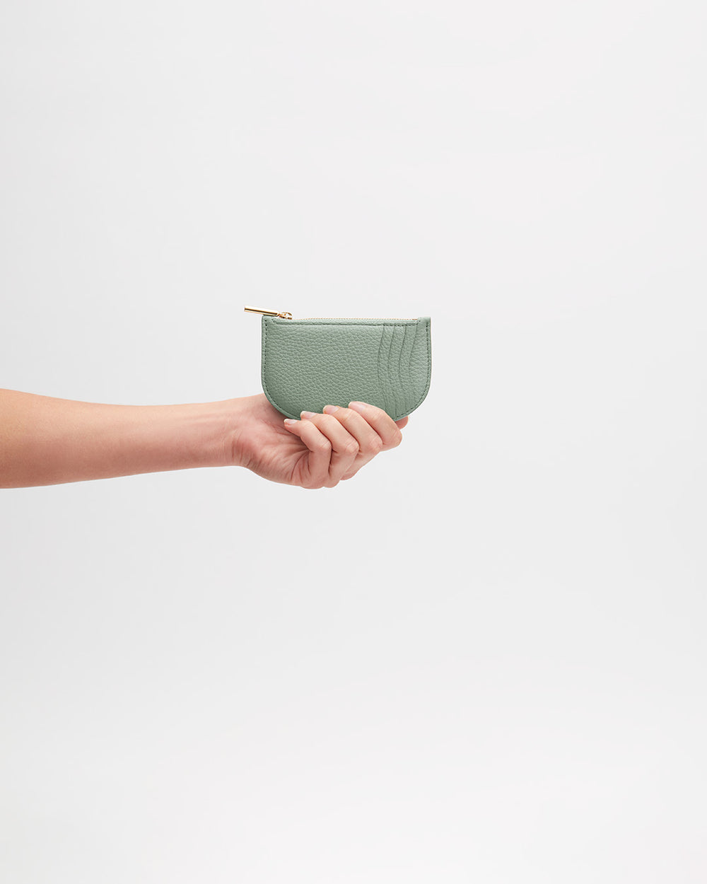 Hand holding a small purse with a zipper.