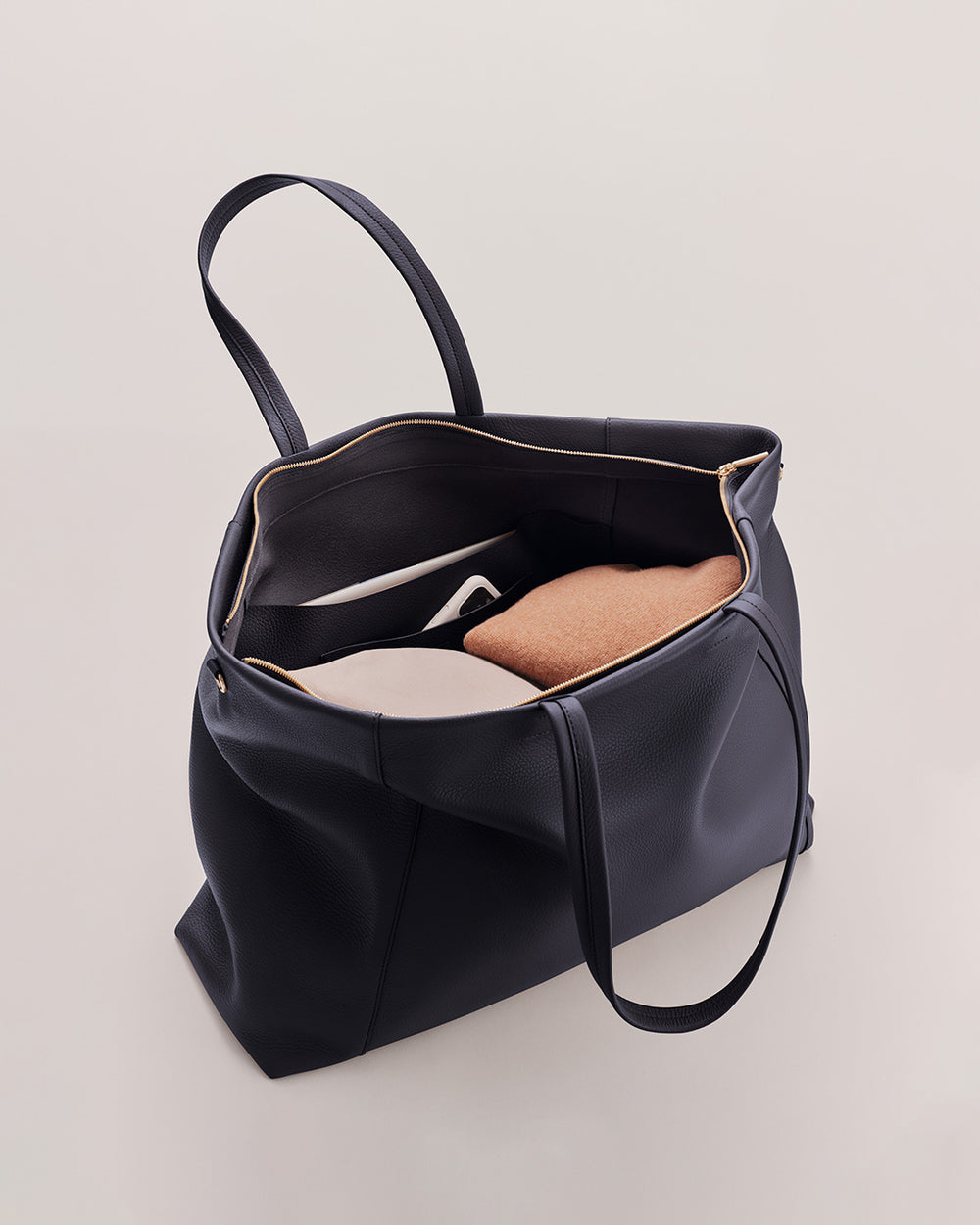 Open handbag with a single shoe inside, against a plain background.