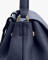 Close-up of a textured handbag with a handle and metal rings.