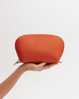 Hand holding a small zipper pouch against a plain background.