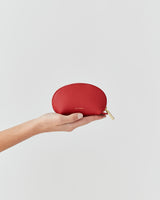 Hand holding a small zippered pouch against a plain background.