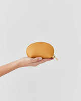 Hand holding a small pouch against a plain background.