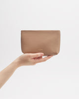 Hand holding a small pouch against a plain background.
