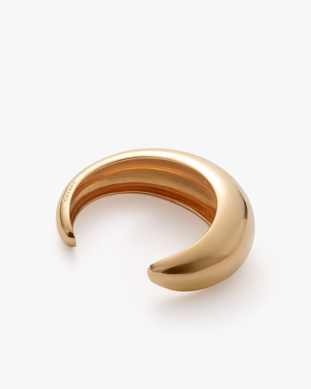 Gold-toned cuff bracelet on a white background.