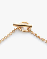 Golden toggle clasp on a chain with engraved brand name.