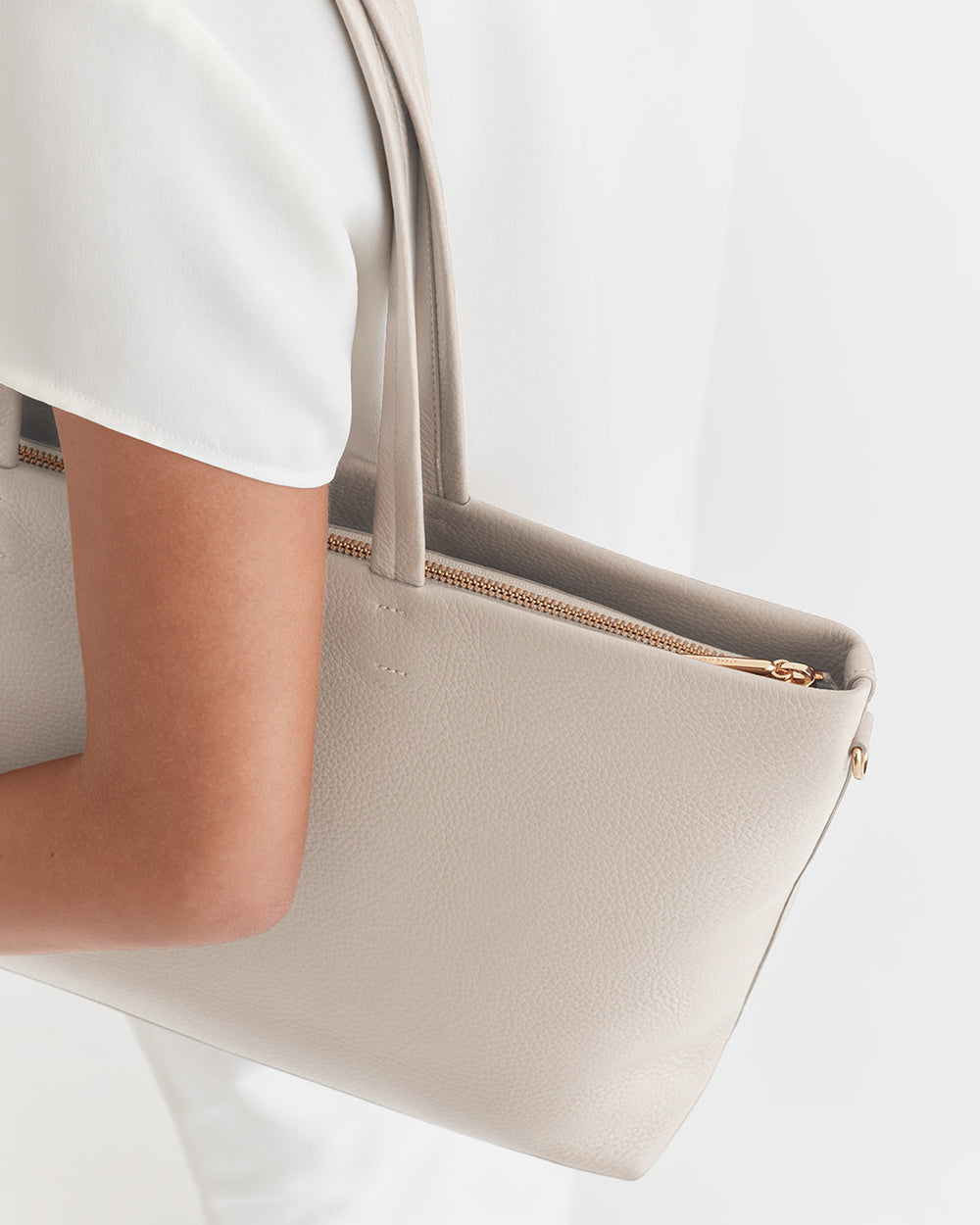 Small Easy Zipper Tote Person holding a handbag by their side.
