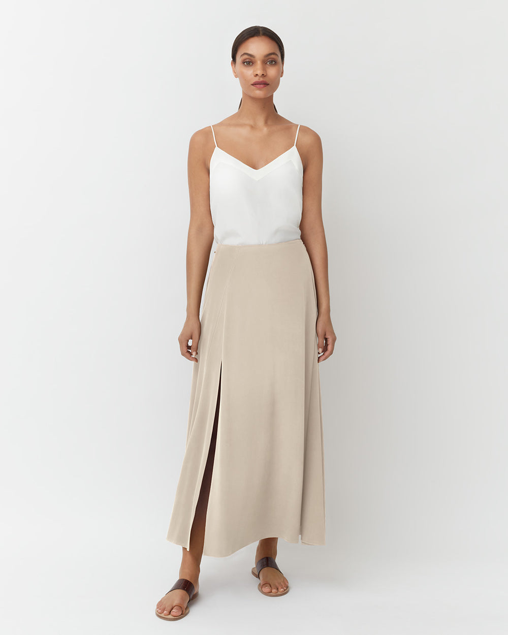 Washable Silk Maxi Skirt Woman standing in a sleeveless top and long skirt with a front slit, wearing sandals.
