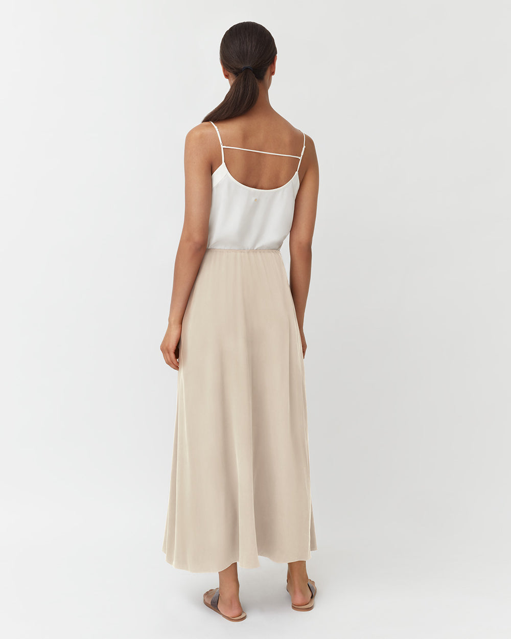 Washable Silk Maxi Skirt Woman standing with her back facing the camera wearing a sleeveless top and long skirt.