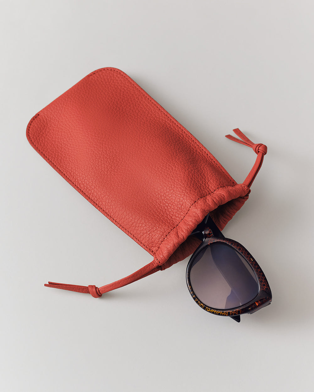 Sunglasses partially inside a soft pouch with drawstrings.