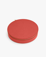 Round zippered leather box on a plain background.
