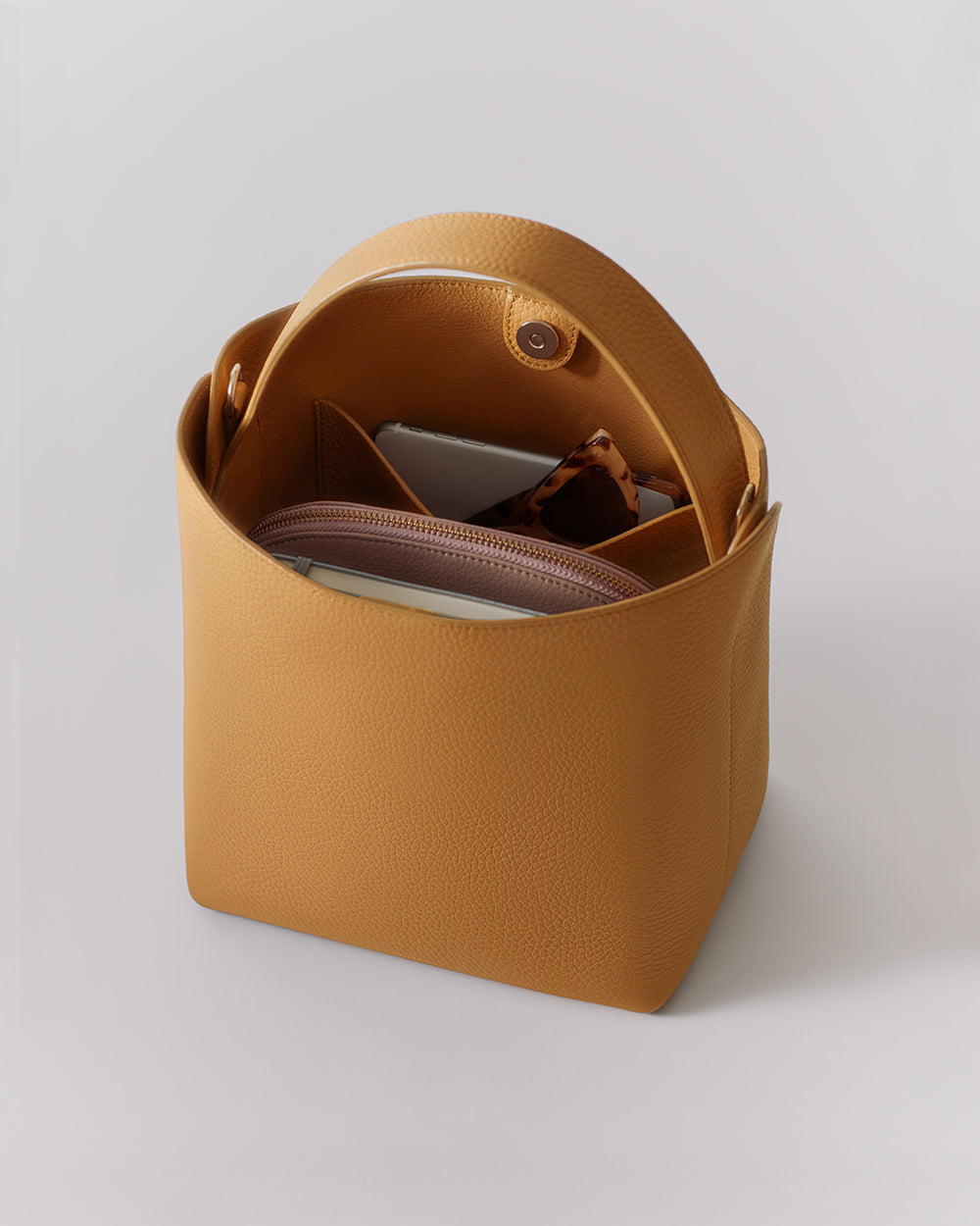 Linea Bucket Bag Open handbag with items inside, including a wallet and a small pouch.