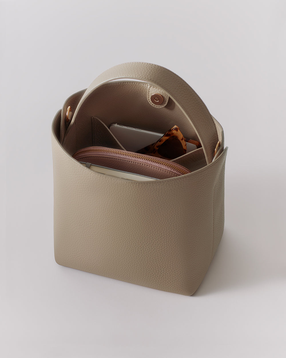 Linea Bucket Bag Open handbag with items inside, including a wallet and a small pouch.