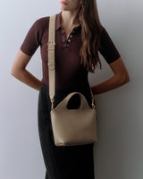 Person with handbag over shoulder wearing a shirt and skirt.