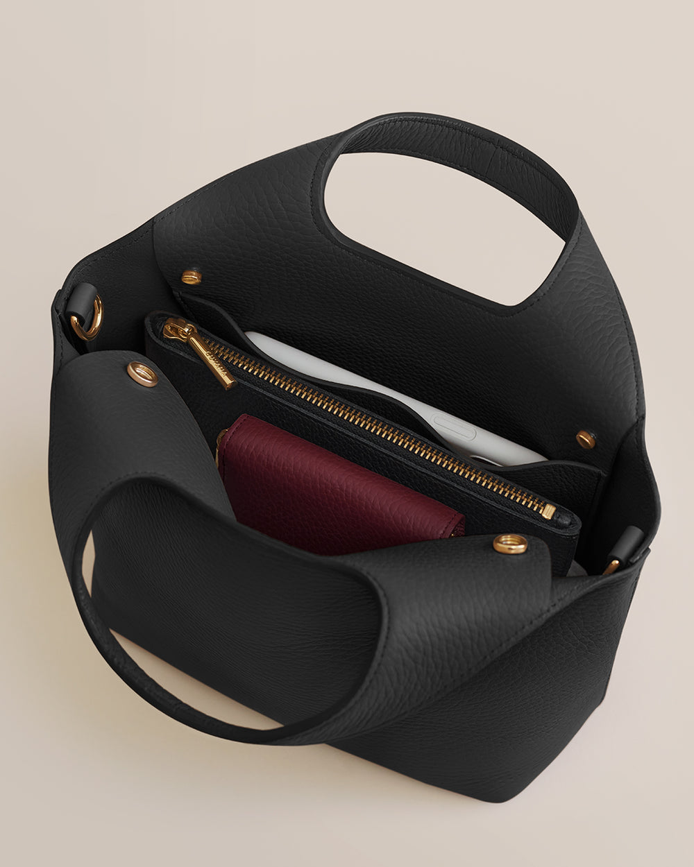 Open handbag showing pockets and zippers with contents inside.