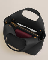 Open handbag showing pockets and zippers with contents inside.