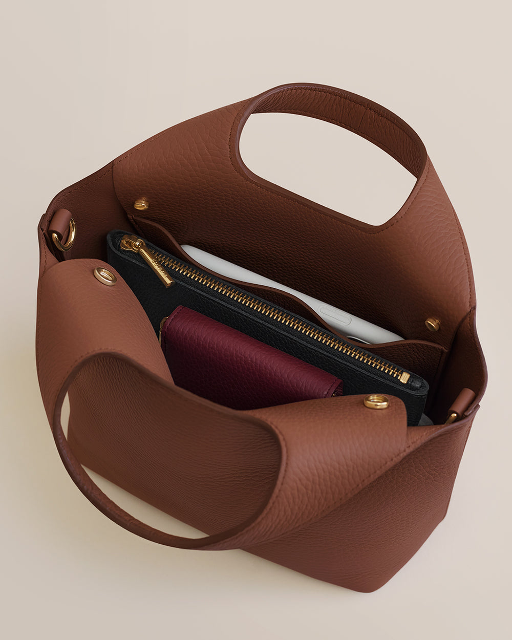 Mini System Tote Open handbag with two zippered pouches and a small book inside