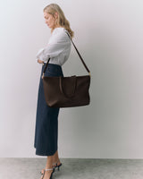 Person with shoulder bag wearing long skirt and heels