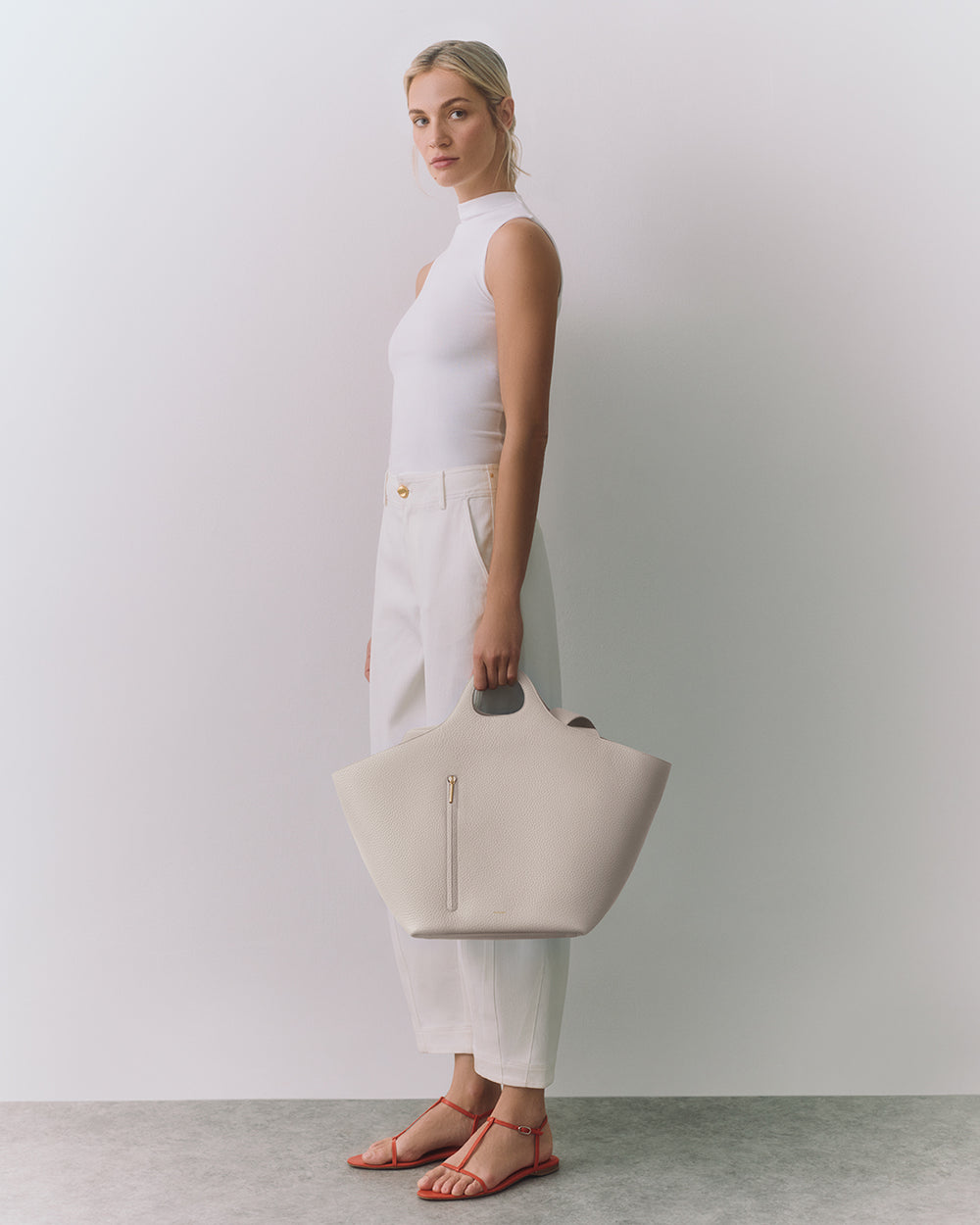 Paloma Tote Person holding a large handbag wearing sleeveless top and pants.