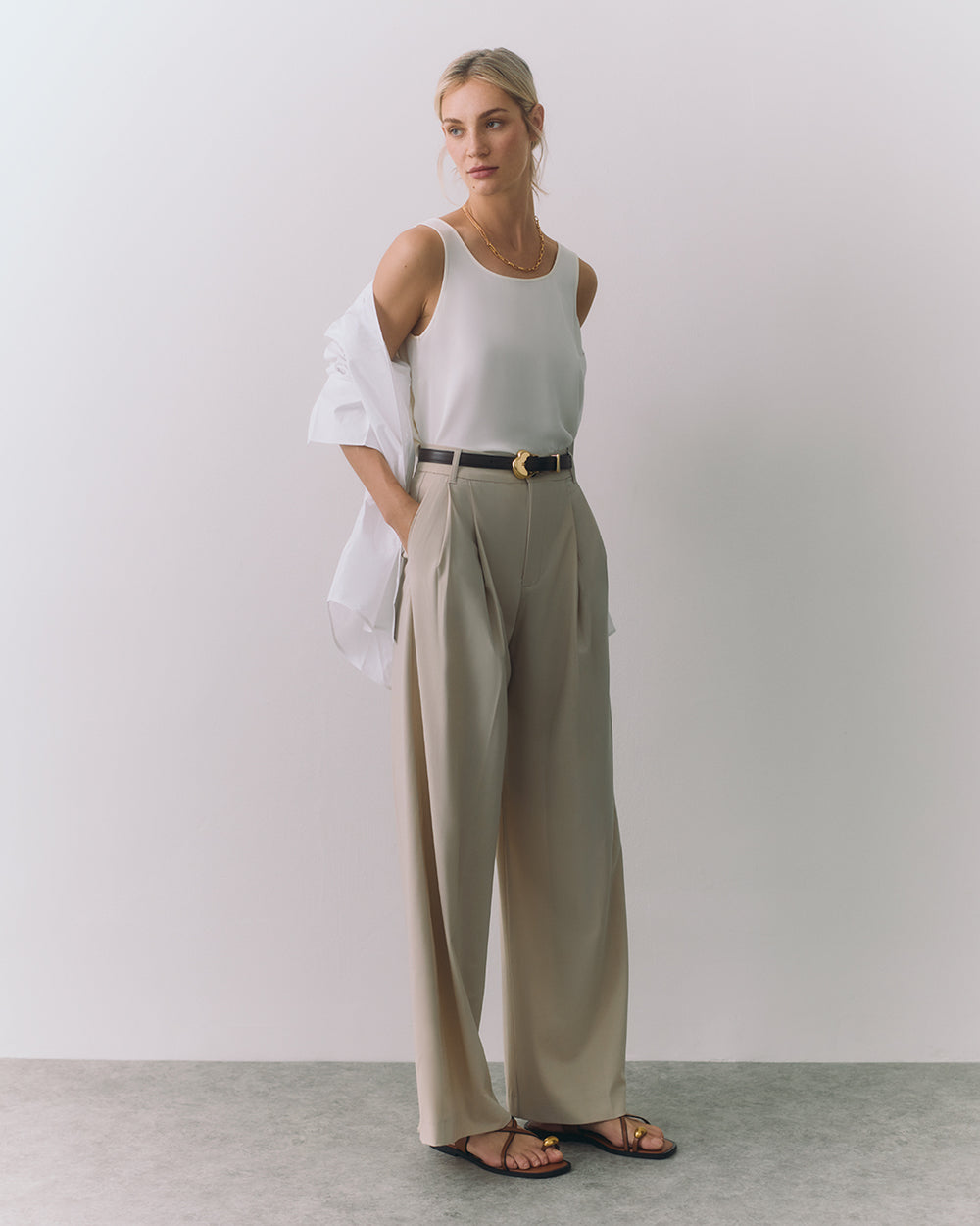 Silk Tank Person wearing a sleeveless top, wide pants, sandals, and a draped jacket over the shoulder.