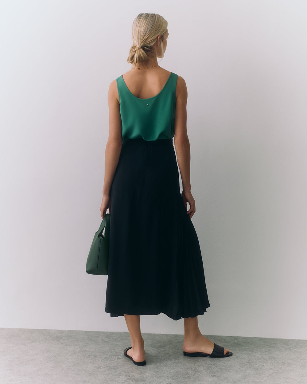 Silk Tank Person in sleeveless top and long skirt holding a bag, standing with back to camera.