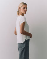 Person in short-sleeve top and jeans is looking back over their shoulder.