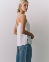 Person wearing a a silk cami and jeans, looking over shoulder.