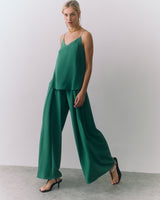 Woman in a a silk cami and wide-leg pants, wearing heels and a necklace.