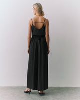 Person in a silk cami and wide leg pants, facing away from the camera.