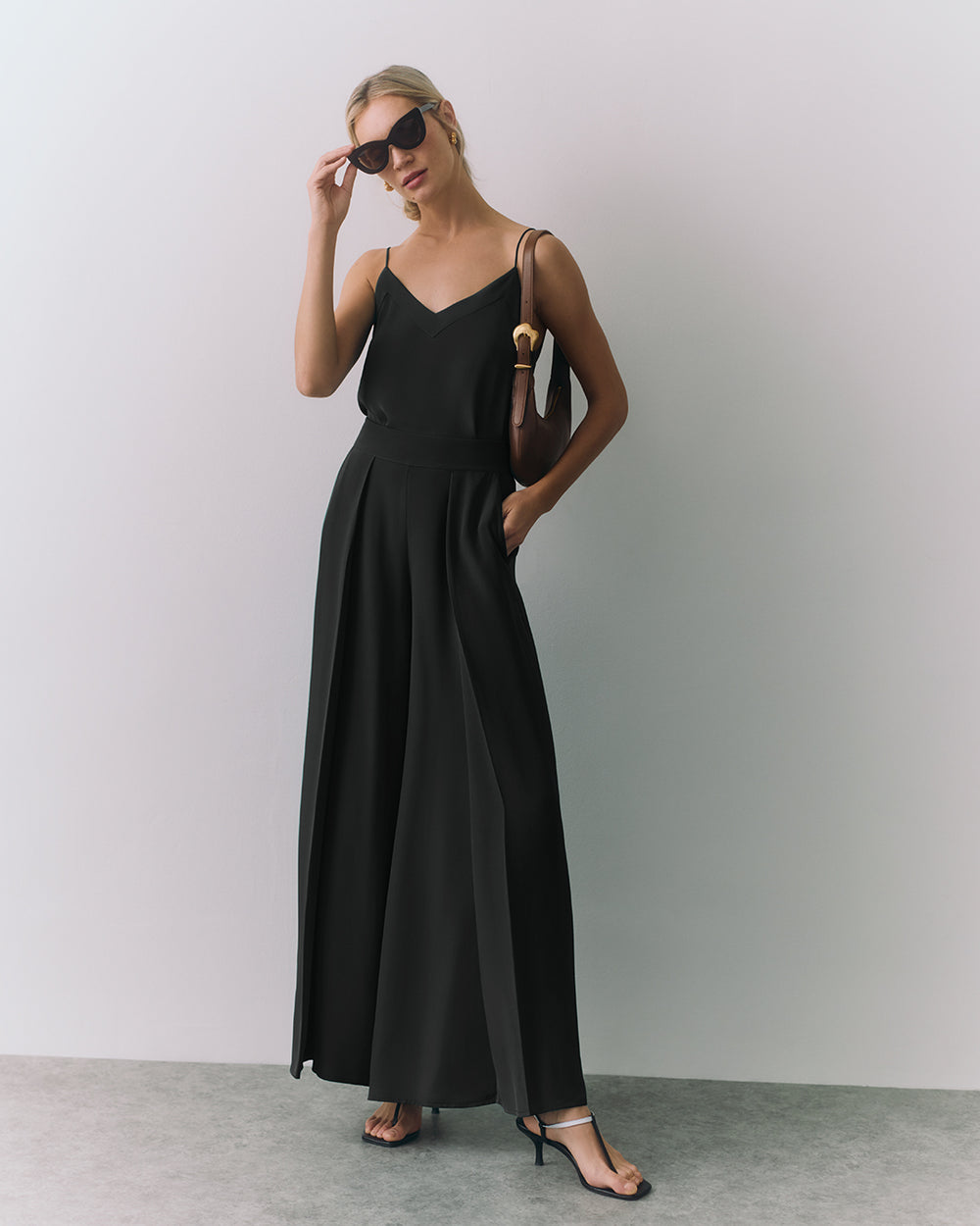 Woman in a a silk cami and wide-leg pants, wearing heels and sunglasses