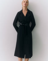 Person wearing a long coat with hands in pockets