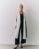 Person wearing long coat over outfit with heels.
