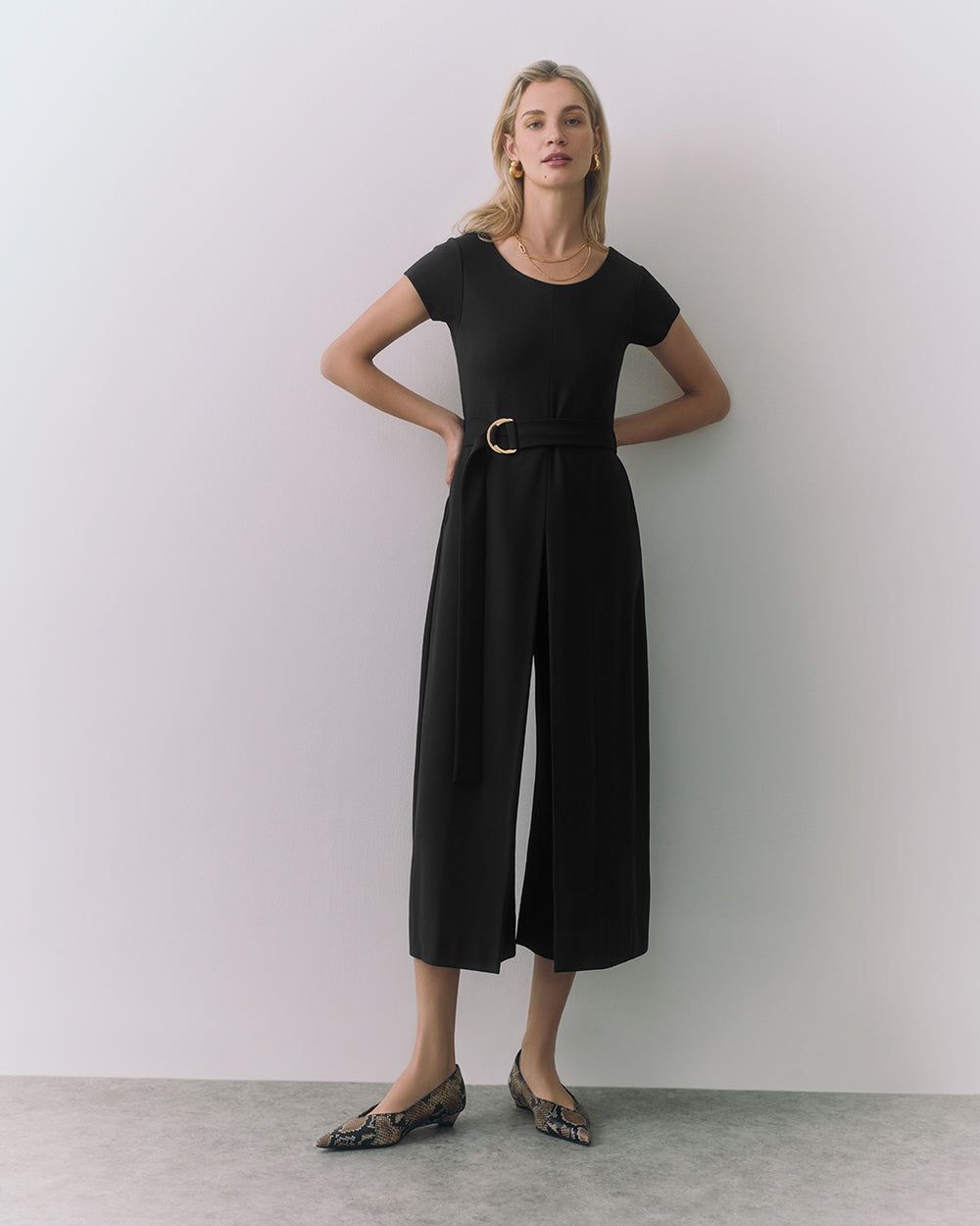 Ponte Pleated Jumpsuit Person in jumpsuit and belt, standing indoors, wearing patterned flats.