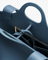 Close-up of an open handbag with a zipper and tied strap inside.